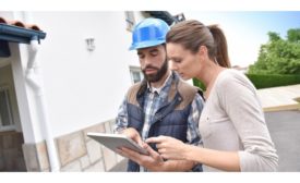 Man in blue hard hat looking at Ipad with woman